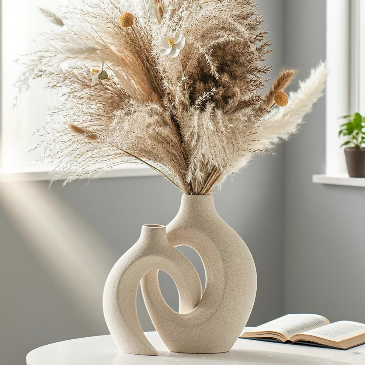 Sculptural beige ceramic vases styled with dried flowers in a light-filled room